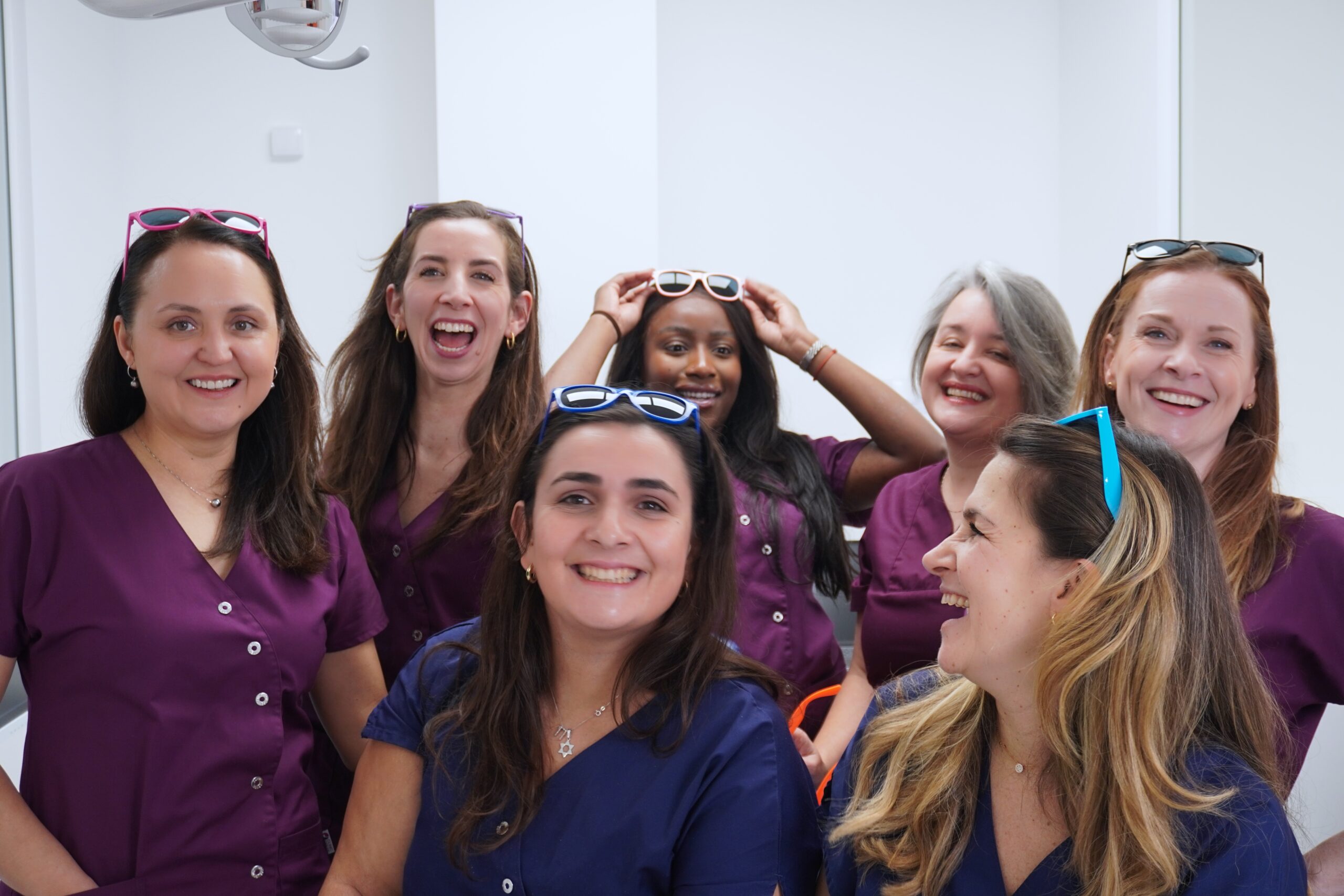 Équipe du cabinet d’orthodontie posant pour une photo de groupe en tenue médicale.
